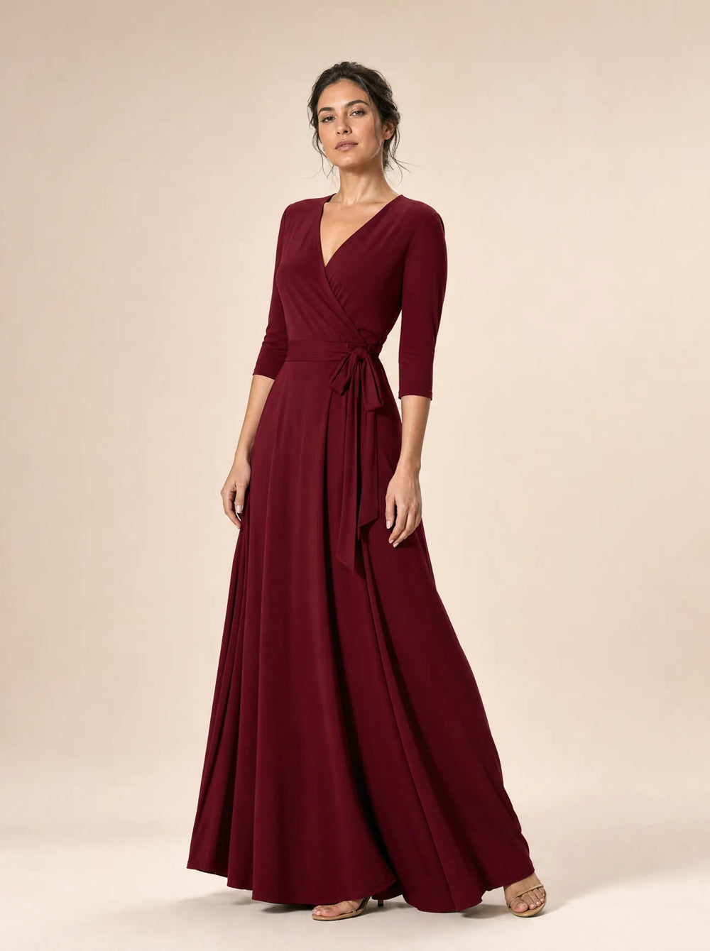 Woman wearing the burgundy Amara three-quarter sleeve wrap maxi dress against a pale beige studio background