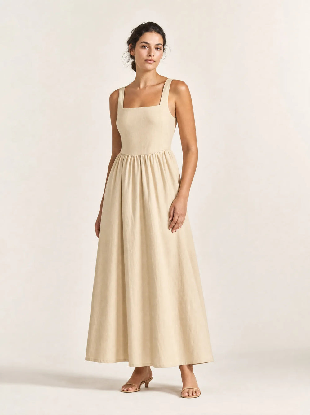 Woman wearing the sand Maren gathered square-neck maxi dress against a warm white studio background
